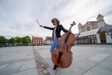 A female musician with a cello on the street © Algimantas