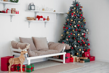 Interior of light living room with Christmas tree, shelves and couch