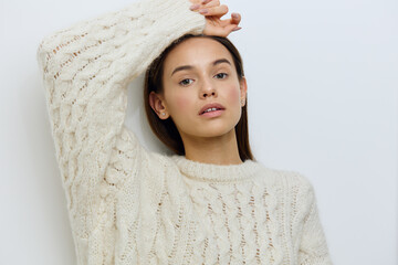 horizontal close-up photo of a sexy, gentle woman in a white sweater on a light background, holding...