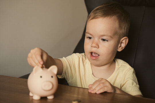 Child puts coins in piggy bank. Smart happy boy saving money in a piggy bank, learning about saving. Money, finances, insurance, and people concept