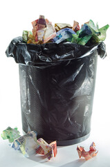 Full trash bin running over of crumpled up rand money notes