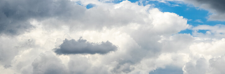 Obraz premium White and gray clouds cover the sky, a small piece of blue sky can be seen through the clouds