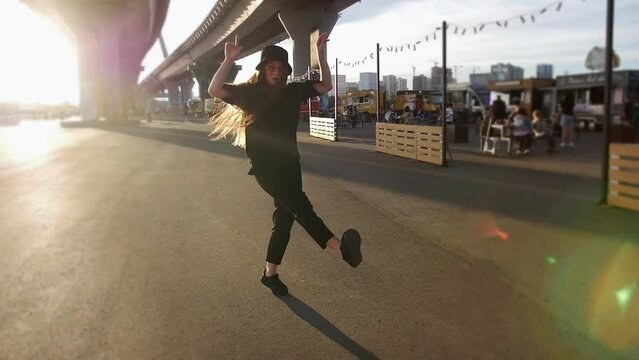 Young woman dancing under the bridge in bright sunlight in slow motion