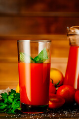 Fresh tomato juice in a glass with tomatoes. Vegetable tomato drink for healthy eating on a wooden background.