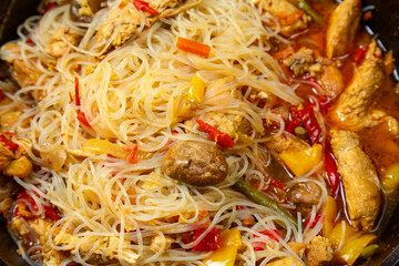 Funchoza with chicken and vegetables in teriyaki sauce garnished with sesame seeds close-up.