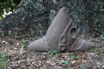Taino Antique Stone Cemi Idol Figure sitting on the ground on top of grass. Taino Indian Mythology.
