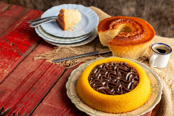 Red wooden table with homemade casserole-style cake and homemade pool-type carrot cake with milk chocolate brigadeiro filling, on top of an old plate with top