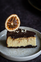 piece of Ukrainian cheesecake syrnyk with chocolate and almond glaze on dark background.