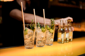 Selective focus on glasses with gin tonic cocktail and bottles on bar counter