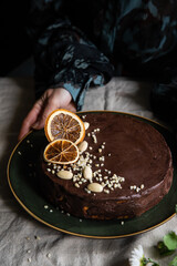 Woman decorating Ukrainian cheesecake syrnyk with chocolate and almond glaze.