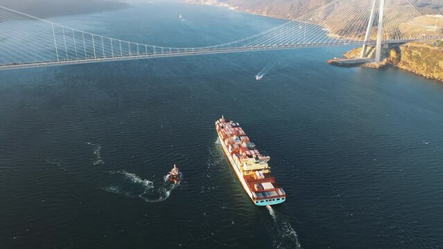 A huge container ship heading towards the Istanbul. Bosphorus Sea, Aerial. Cargo vessel underways under the Yavuz Sultan Selim Bridge in the early morning
