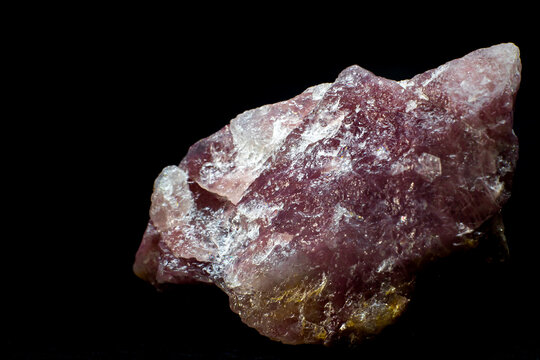 Close-up macro pink aventurine, strawberry quartz raw crystal stone, pink quartz with lepidolite mica inclusions isolated on a black background surface 