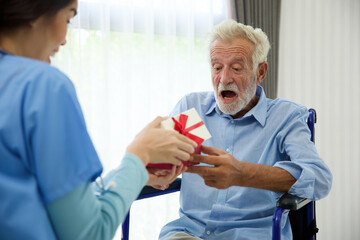 senior man taking a gift box from caregiver for happy birthday
