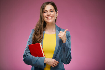 Smiling school teacher woman holding book and showing thumb up. Isolated advertising portrait.