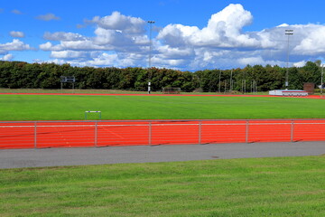 Part of a Stadium or sports arena. Red running tracks next to a green lawn. Sunny day outside. Bålsta, Stockholm, Sweden, Scandinavia, Europe.