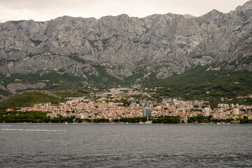 Old, stone lighthouse on the edge of coastline in front of town of Makarska, Croatia under mighty...