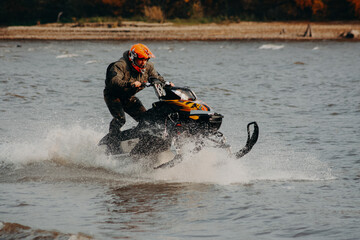 sportsman on a snowmobile rides on the water