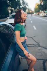 Fototapeta na wymiar Beautiful fashionable young woman in glasses posing near car