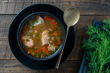 Fresh salmon fish soup with carrots, potatoes and red peppers in plate. Tasty dinner consists of a fish soup with salmon