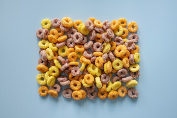 Dry breakfast from corn rings in the form of a frame on a blue background. Place for text. Flatley.