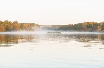 Island in the morning fog on the lake, river.