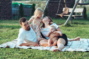 Happy family and small children on a blanket in the grass at summer