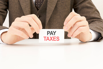 businessman presenting 'PAY TAXES' word on white card