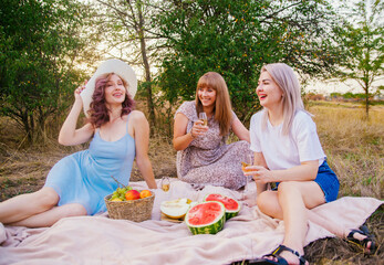 Women clink glasses with white wine or champagne at an outdoor party. Women's hands hold transparent glasses with an alcoholic drink at a picnic.A cheerful company of girls, a bachelorette party.