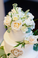 Obraz na płótnie Canvas Close up of tasty wedding cake with white glaze and fresh flowers composition