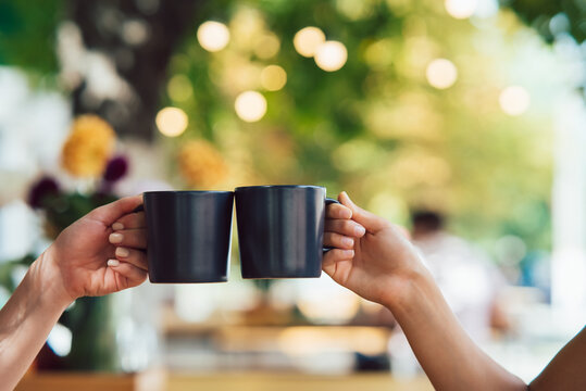 Closeup image of a people clinking coffee cups together in cafe