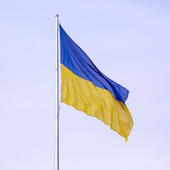 waving in the wind the national flag of Ukraine against the blue sky
