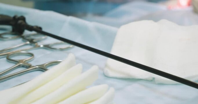 On a sterile table covered with a blue cloth lie laparoscopic and surgical instruments stained with blood. The used instrument lies next to the surgical table. The concept of laparoscopy.