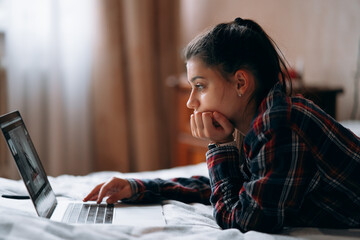 Young woman work while with laptop lying on bed