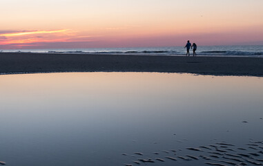 Sunrise silhouette of a couple walking on Coligny beach, Hilton Head, South Carolina.