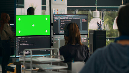 Woman programer looking at greenscreen and code on terminal window, working with chromakey display and html script in it office. Using isolated mockup copyspace on software development. Tripod shot.
