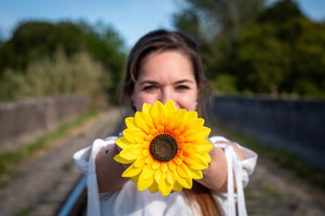 Mujer joven con vestido blanco sosteniendo un girasol en un día soleado de primavera. Fotografía...
