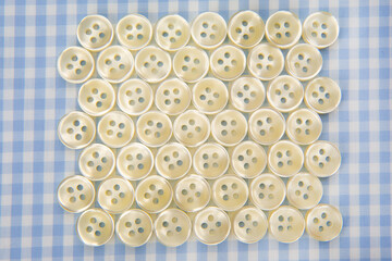 Plastic shiny buttons for clothes on a fabric background. Fashion and clothing. Factory industry