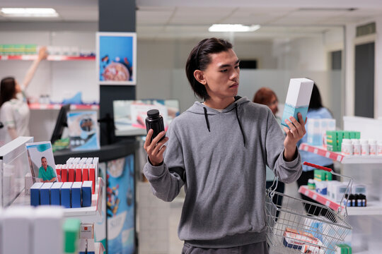 Young adult checking medication packages, feeling indecisive about box of supplements or bottle of pills. Pharmacy customer looking at medicaments and healthcare products in drugstore.