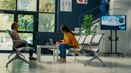 Female nurse taking elderly patient to attend medical appointment, starting checkup consultation to help woman with disease. Person in waiting lobby at health center. Tripod shot.