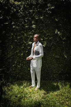 a black woman dressed fashionable posing for a portrait in a garden