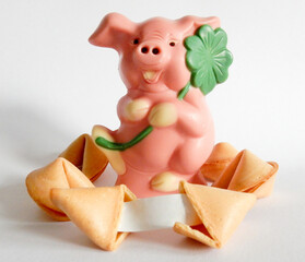 Rosa Schweinchen aus Schokolade mit Kleeblatt und Glückskekse, ein Glückskeks geöffnet mit blanko Papierstreifen zum beschriften,
Silvester und Glücksbringer Karte,
