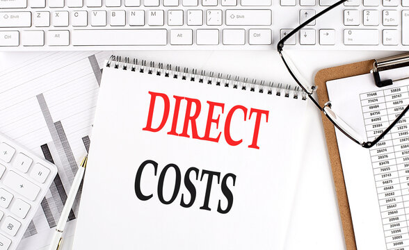 Text DIRECT COSTS on Office desk table with keyboard, notepad and analysis chart on white background.