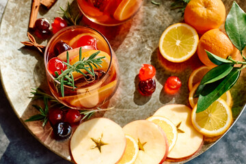 Fototapeta na wymiar Mulled wine or christmas sangria with aromatic spices, apple, cherry and citrus fruits. Traditional Christmas festive warming spiced drink with orange, berry, cinnamon, cardamom and anise.