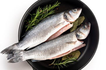 Sea bass fish. Two peeled raw sea bass, spices and rosemary branches in a skillet