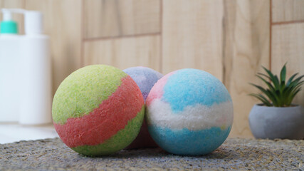 Colorful bath bombs on wicker mat in bathroom, closeup