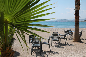 Beautiful view of chairs and tables on sandy beach near sea