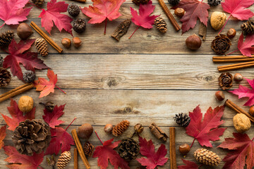 Flatlay autumn border frame including red maple leaves, nuts and pinecones.