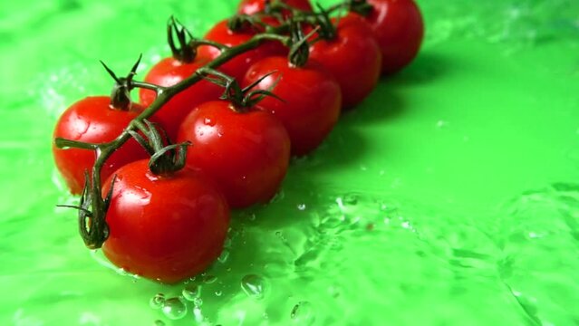The falling cherry tomatoes in water. Slow motion.