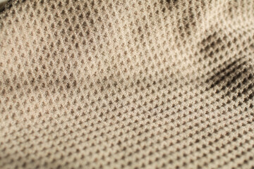 Beige waffle weave cotton fabric with light and shadow. Closeup of light natural cotton texture pattern for background.