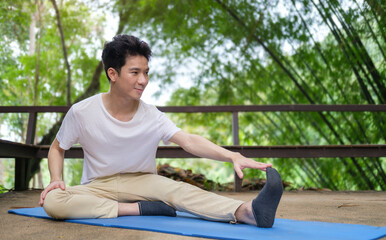 Positive man stretching,  practicing yoga at outdoor. Yoga,fitness, healthy lifestyle concept.